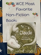 A school bulletin board with a basketball-themed background. A white sign with colorful balloon graphics reads "WCE Most Favorite Non-Fiction Book" in blue text. Taped below is the cover of "Claude: The True Story of a White Alligator" by Emma Bland Smith